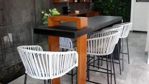 A modern kitchen with a black countertop, white wicker chairs, and a wooden bar area. - ILLUSION XPRESS Downtown Playa (Playa del Carmen)