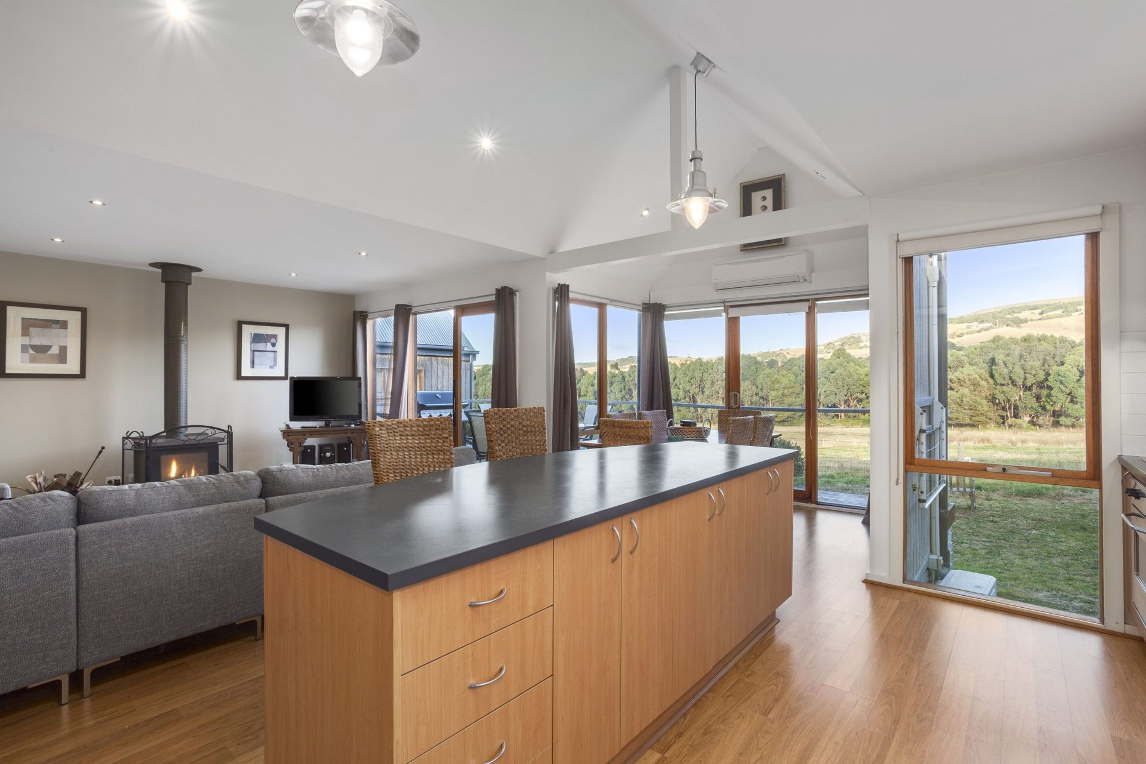 A spacious kitchen with a large island, wooden cabinets, and a view of the outdoors.