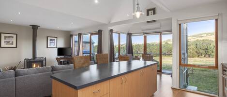 A spacious kitchen with a large island, wooden cabinets, and a view of the outdoors.