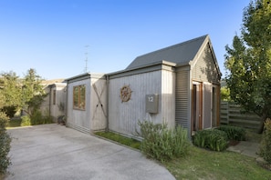 A building with a grey exterior, a number '12' sign, and a door with a mesh screen. - Otway Vista 12 (Apollo Bay)