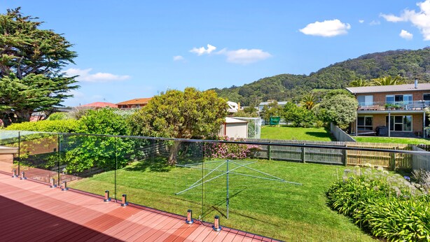 A residential area with a well-maintained lawn, a tennis court, and a view of a hilly landscape. - Casino Views (Apollo Bay)