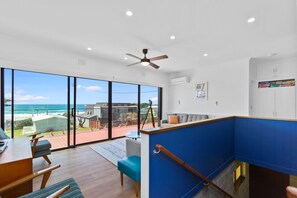A modern interior with a balcony overlooking a beach, a ceiling fan, and a collection of board games. - Casino Views (Apollo Bay)