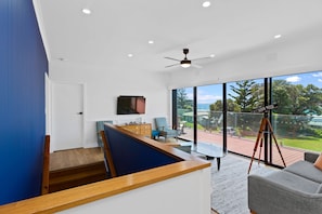 A modern interior with a wooden staircase, a flat-screen TV, a dining area, and a balcony with a telescope. - Casino Views (Apollo Bay)