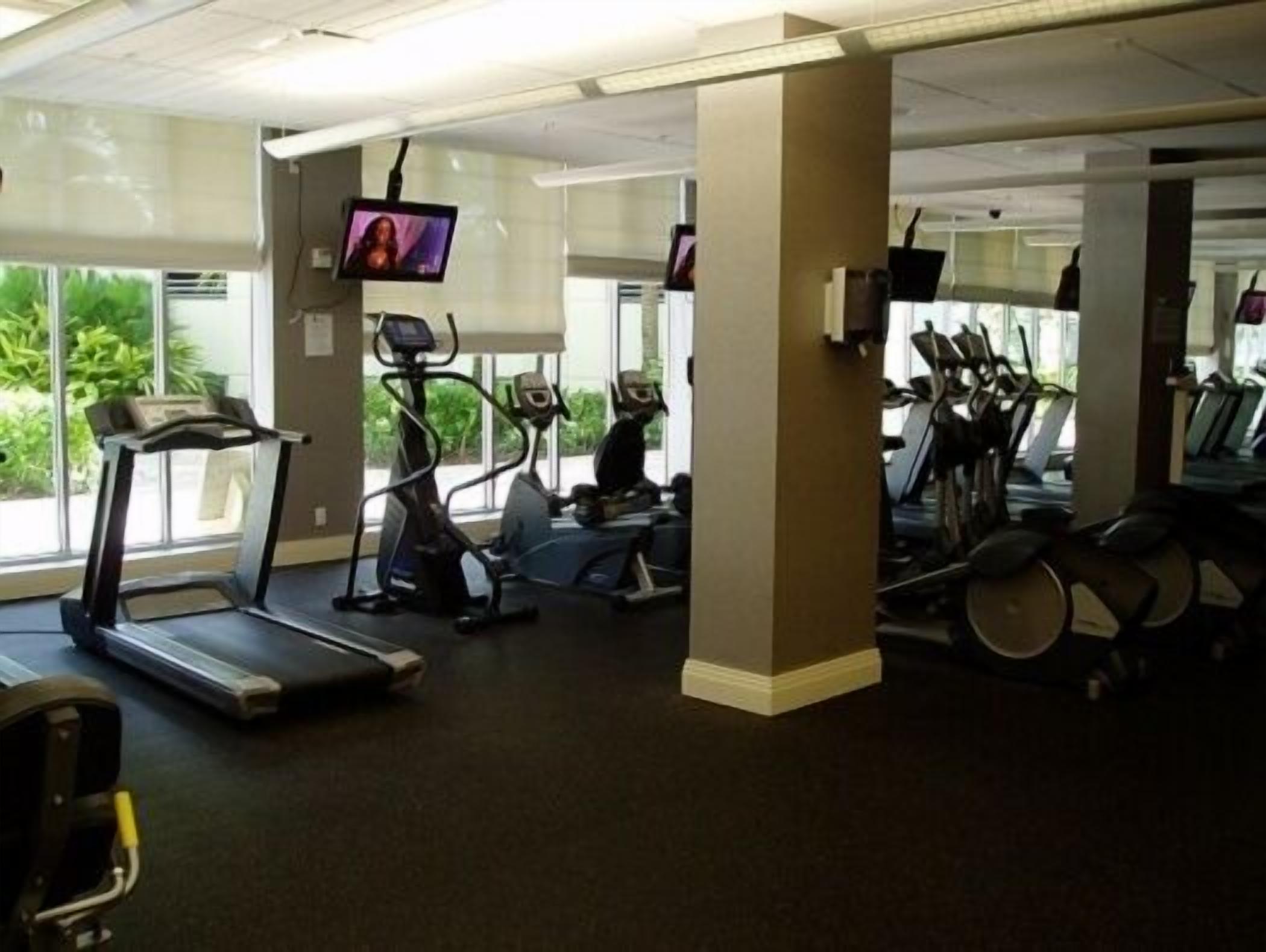 Un gimnasio con cintas de correr, elípticas y bicicletas estáticas.