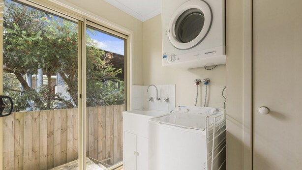 A laundry room with a washing machine, a dryer, and a large window. - Summer Breeze (Apollo Bay)