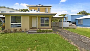 A two-story house with a front porch, large windows, and a visible garage. - Summer Breeze (Apollo Bay)
