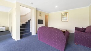 A room with a staircase, two purple sofas, a small table, and a framed picture on the wall. - Summer Breeze (Apollo Bay)