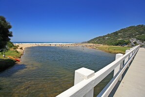 A river leading to a beach with a bridge in the foreground.