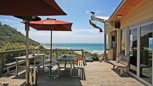 Una terrazza in legno con tavoli e panche che si affaccia su una spiaggia.