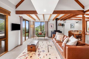 A spacious living room with a fireplace, a television, and a dining area with wooden furniture.