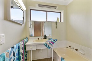A bathroom with a bathtub, a sink, a mirror, and a window. - 1 at Fifty Nine  Beach Classic  in Lorne (Lorne)