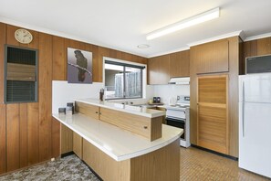 A modern kitchen with wooden paneling, a central island, a built-in oven, and a refrigerator. - 1 at Fifty Nine Beach Classic in Lorne (Lorne)