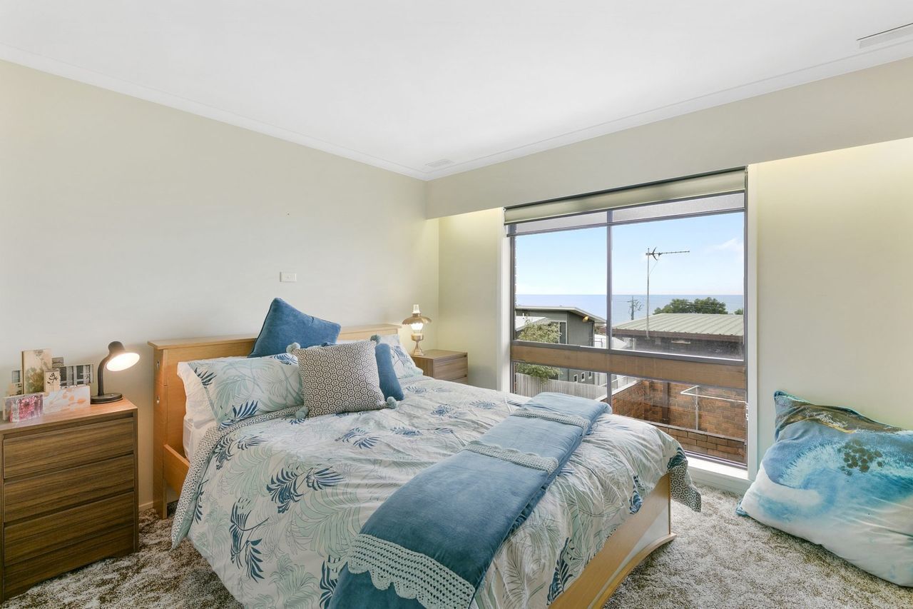 A bedroom with a bed, bedside tables, a nightstand, a window with a view, and a balcony.