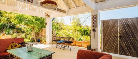 A covered outdoor seating area with a table, chairs, and a sofa.