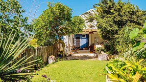 A house with a front yard, a wooden fence, and various plants. - The blue beach house (Quinns Rocks)