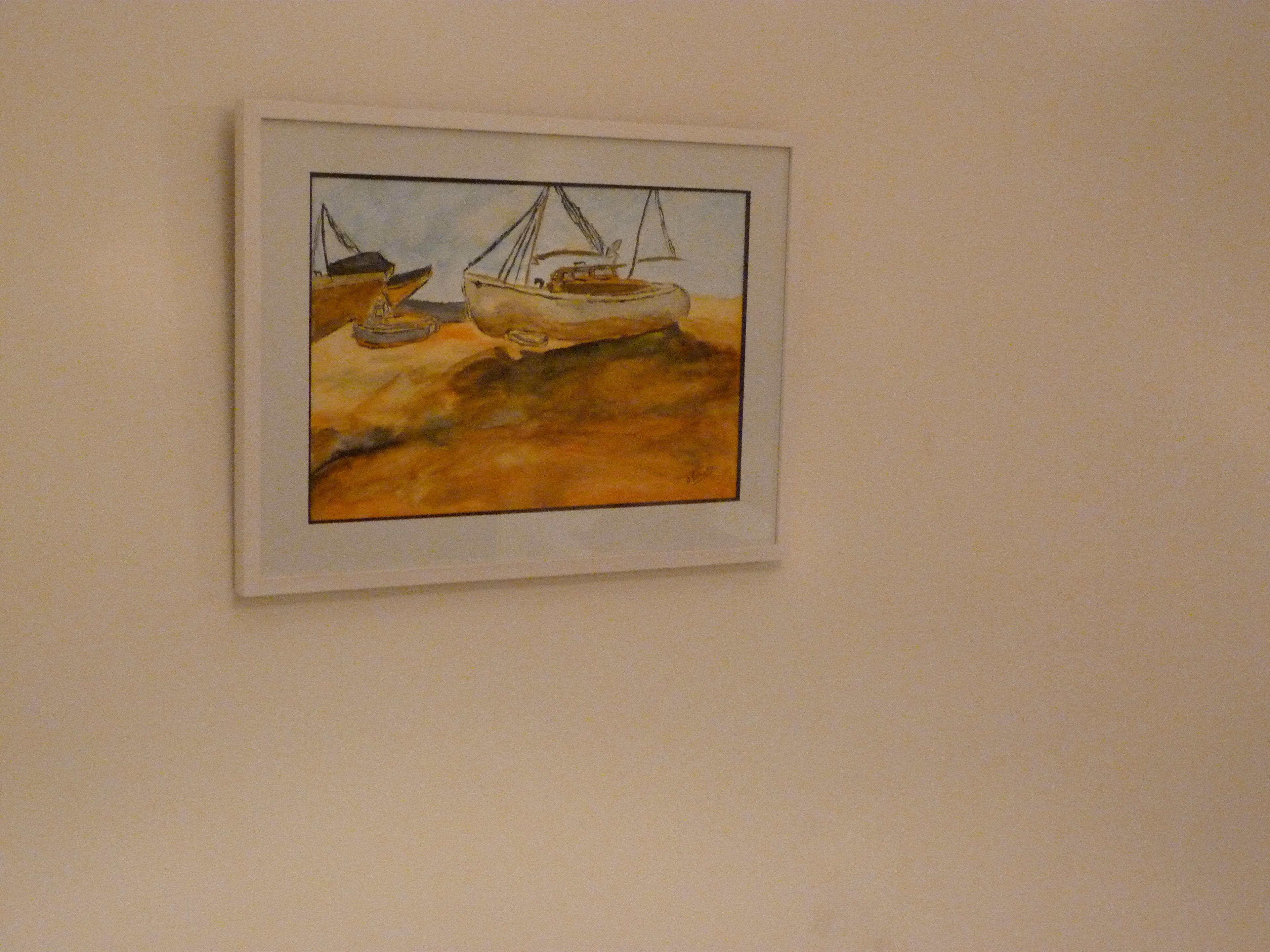 A framed artwork of a boat on a rocky shore.