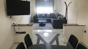 A modern living room with a sofa set, a glass coffee table, and a TV mounted on the wall. - Résidence Les Ambassadeurs (Rabat)
