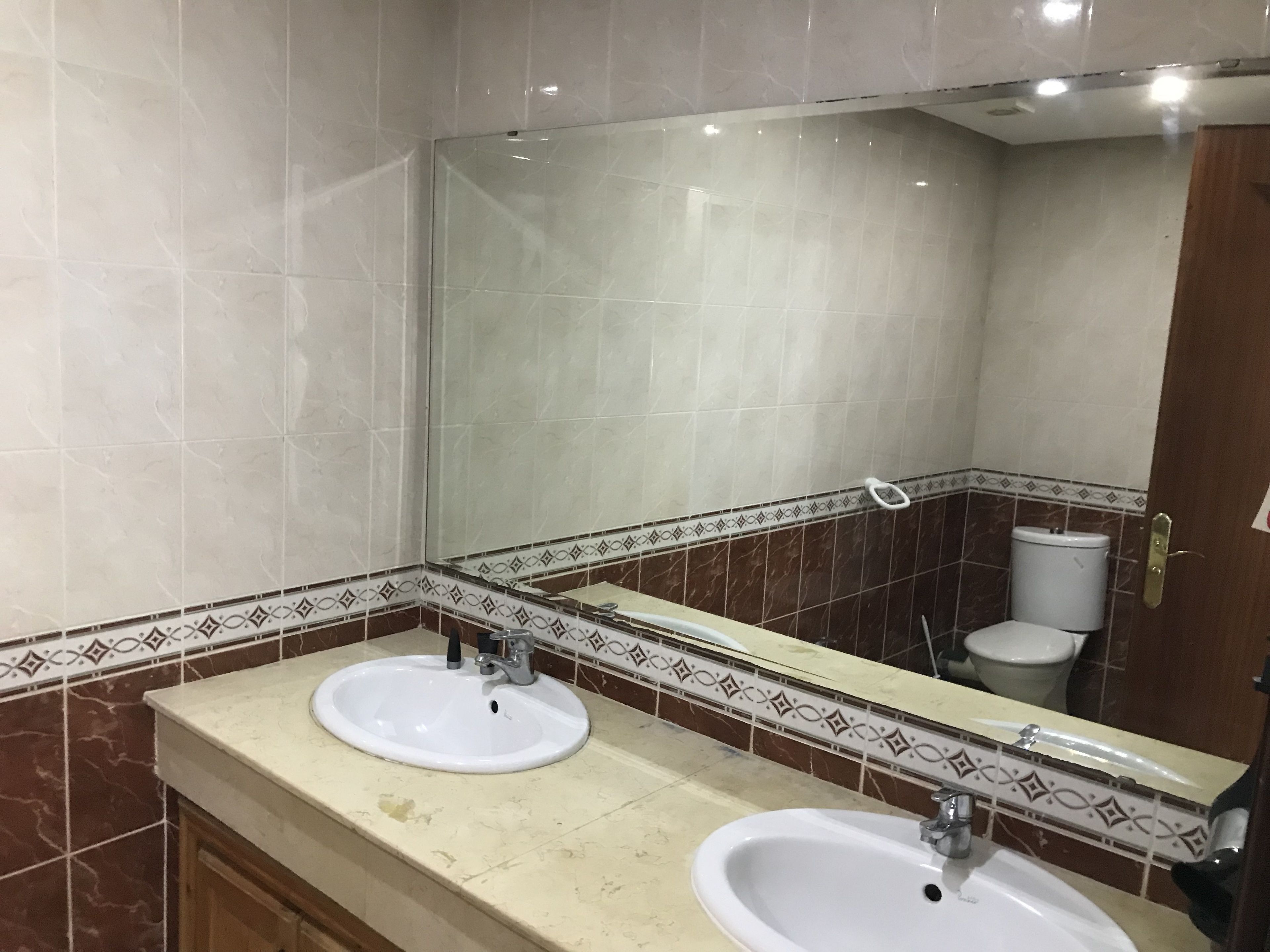 A bathroom with two sinks, a mirror, and a toilet.