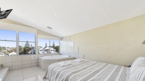 Une chambre moderne avec un grand lit, une baignoire et une vue sur un quartier résidentiel.