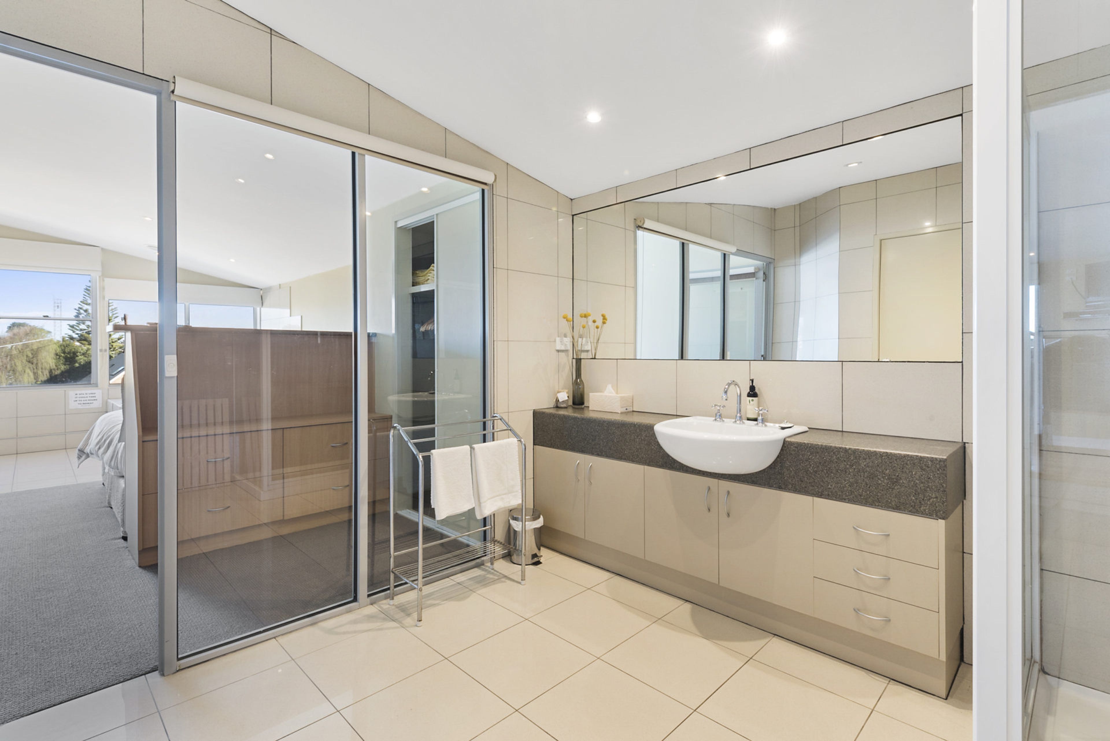 Une salle de bain moderne avec une douche à parois de verre, un lavabo avec un miroir et un meuble-lavabo avec des placards.
