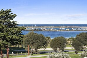 A coastal marina with boats docked, surrounded by greenery and a clear sky. - Balconies At The Butter Factory (Apollo Bay)