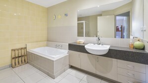 Une salle de bain avec une baignoire, un lavabo et un miroir.