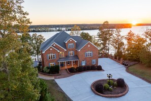 A large brick house with a wrap-around porch and a driveway leading to a circular driveway. - Executive Mansion at Lake Gaston sleeps 40 and has HEATED POOL. (Bracey)