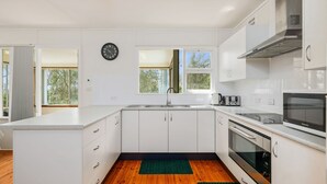 A modern kitchen with white cabinets, a built-in oven, a microwave, and a sink. - On Collingwood Beach  by Book Jervis Bay - Upstairs Apartment (Vincentia)