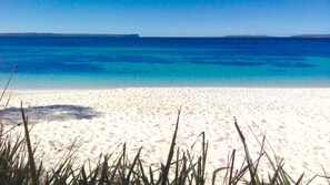 Une plage de sable blanc bordée d’une eau d’un bleu cristallin.