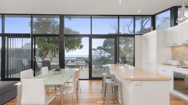 Enjoy a panoramic view of the surrounding landscape from the expansive glass doors in this kitchen, featuring a central island with sink and ample counter space.