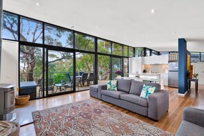 Un salon moderne avec un canapé gris, un tapis à motifs et un coin repas doté d’un espace détente extérieur.