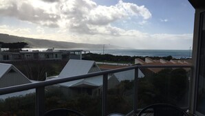 Un balcon avec une table et des chaises, donnant sur un quartier résidentiel et la mer.