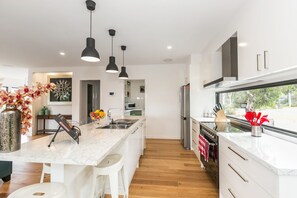 Eine moderne Küche mit einer zentralen Kochinsel, Pendelleuchten und Blick ins Freie.