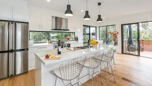 A modern kitchen with a large island, stainless steel appliances, and pendant lighting. - Allawah (Lorne)