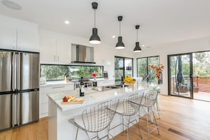 A modern kitchen with a large island, stainless steel appliances, and pendant lighting. - Allawah (Lorne)