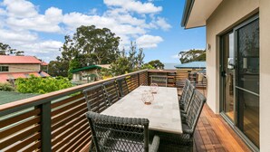 A balcony with a table and chairs, a view of the sky, and surrounding buildings. - Allawah (Lorne)