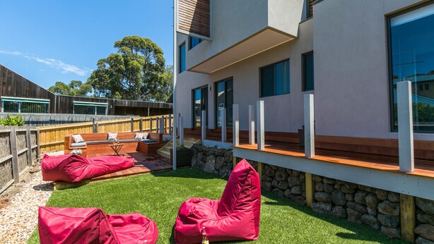 A modern outdoor seating area with built-in benches and a stone wall. - Allawah (Lorne)