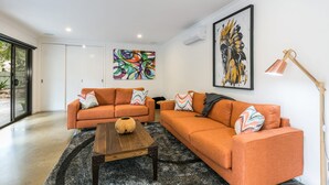 A modern living room with two orange sofas, a wooden coffee table, and a black and white rug. - Allawah (Lorne)
