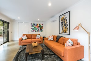 A modern living room with two orange sofas, a wooden coffee table, and a black and white rug. - Allawah (Lorne)