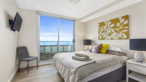 Una camera da letto con un letto, una sedia, una scrivania, una televisione e un'ampia finestra.