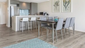 Una cucina moderna con isola centrale, sgabelli da bar e tavolo da pranzo con sedie.