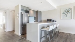 Een moderne keuken met een centraal eiland, roestvrijstalen apparatuur en een bar met krukken.