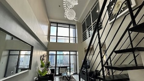 Un interior moderno con una escalera, ventanas amplias y una araña.