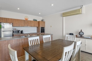 Eine moderne Küche mit Holzschränken, einem Edelstahl-Kühlschrank, einer Mikrowelle und einem eingebauten Backofen.