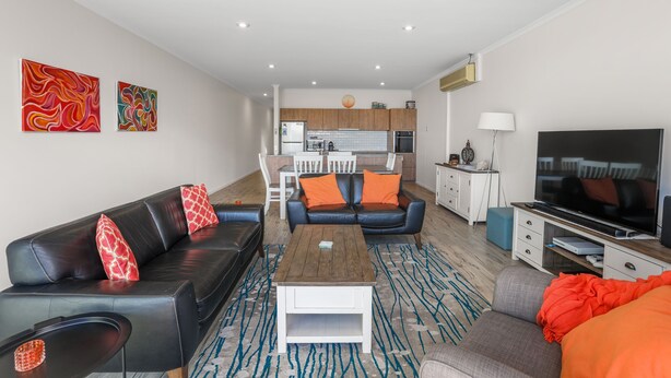 Ein modernes Wohnzimmer mit einem schwarzen Ledersofa, einem Holztisch und einem Fernseher.