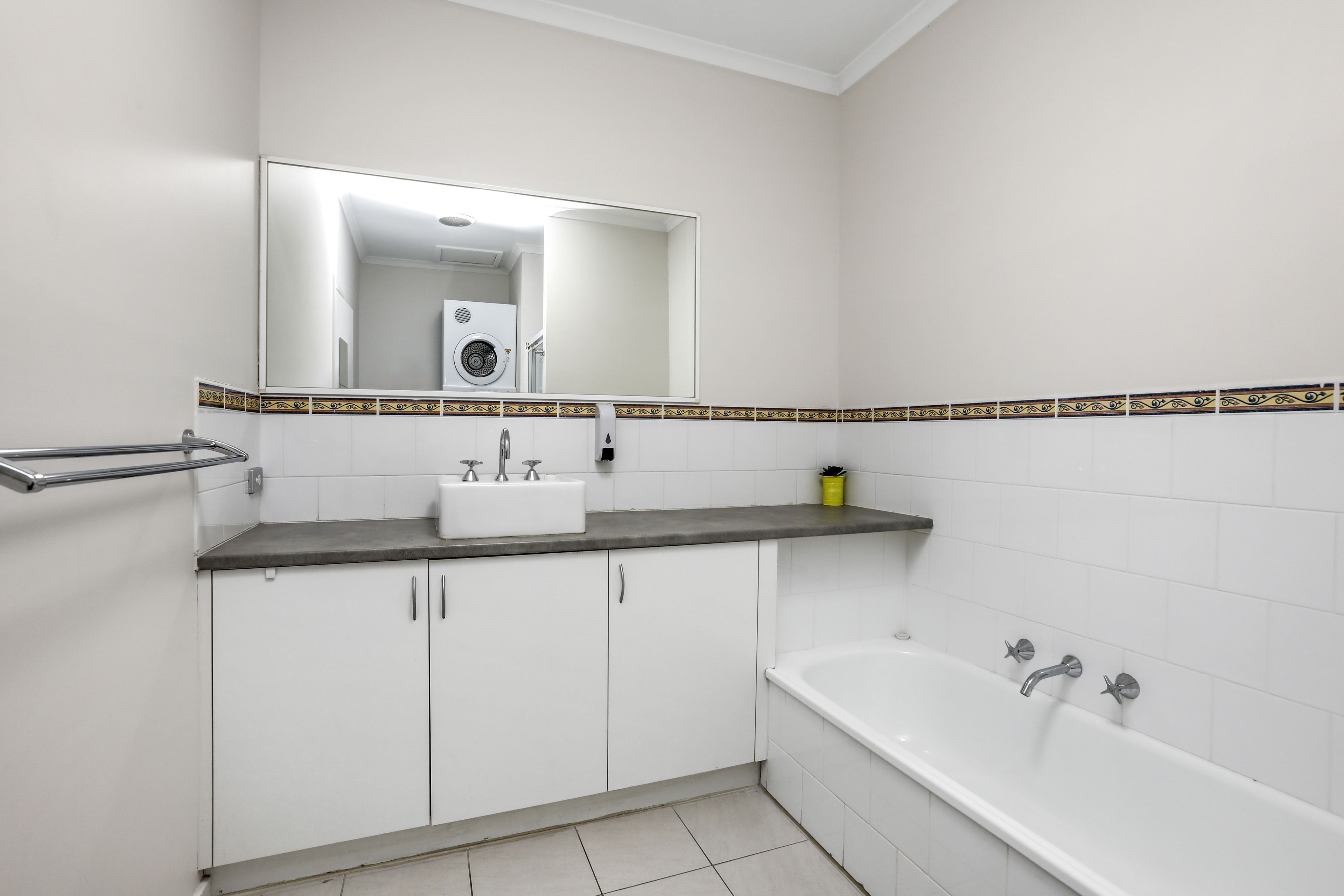 A bathroom with a white sink, a mirror, a bathtub, and a towel rack.