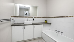 Ein Badezimmer mit einem weißen Waschbecken, einem Spiegel, einer Badewanne und einem Handtuchhalter.