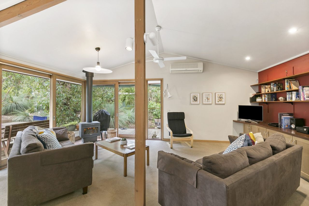 A modern living room with a sofa, a chair, a television, and a bookshelf.
