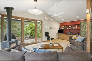 A modern living room with a fireplace, a ceiling fan, and a television.