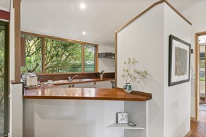 Eine moderne Küche mit einer Holzarbeitsplatte, einem Spülbecken und einem Fenster mit Blick auf Grünflächen.